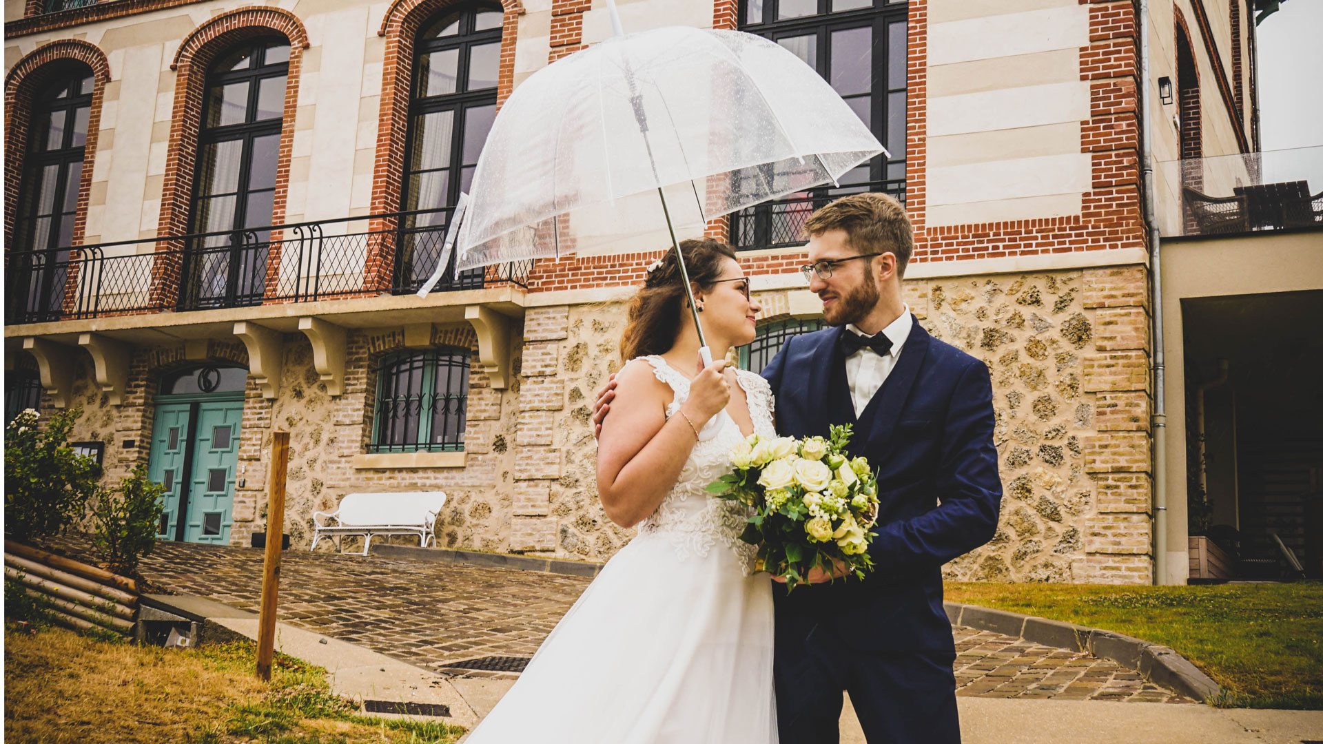 Les mariés sous la pluie avec un parapluie transparent. Perfect Moment by A Wedding planner Reims